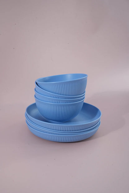 A set of light blue ribbed bowls and matching plates stacked together on a plain light gray studio background.