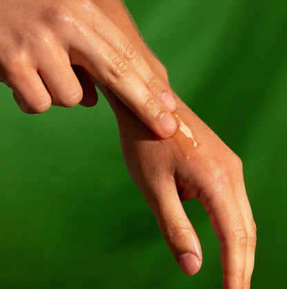 Person applying hemp ozone face balm on hand, natural skin care treatment, with green background